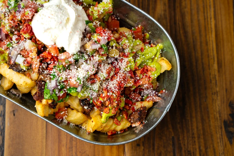 Steak fries topped with cheese and meat from El Fogón Taquería's menu.