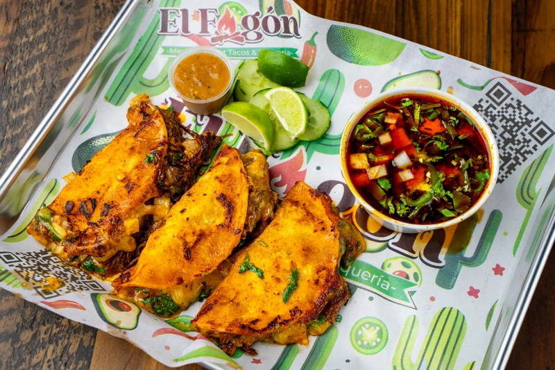 Juicy birria tacos with consommé at El Fogón Taquería, a Mexican favorite.